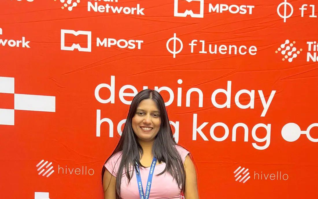 Shilika Jain in front of the DePIN Day Hong Kong sponsor wall