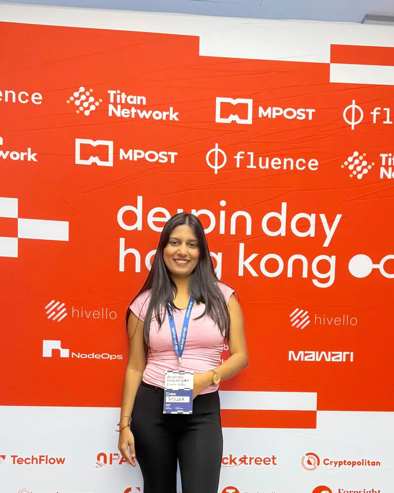 Shilika Jain in front of the DePIN Day Hong Kong sponsor wall