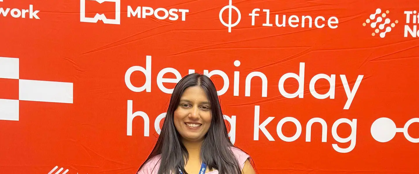 Shilika Jain in front of the DePIN Day Hong Kong sponsor wall