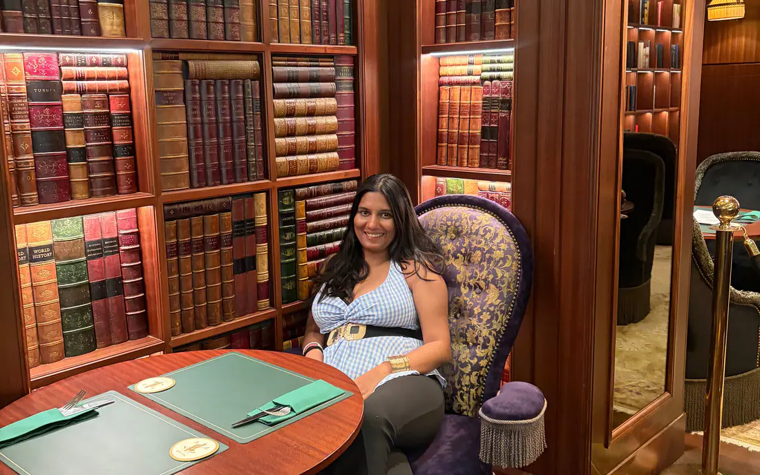 Shilika Jain seated in a wood-panelled library lounge lined with leather-bound books