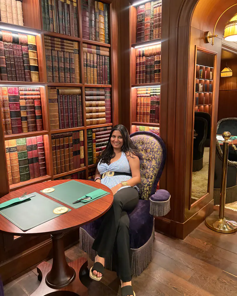 Shilika Jain seated in a wood-panelled library lounge lined with leather-bound books