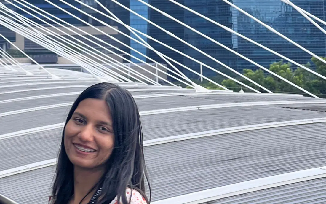 Shilika Jain on a Marina Bay footbridge in Singapore, wearing a conference lanyard