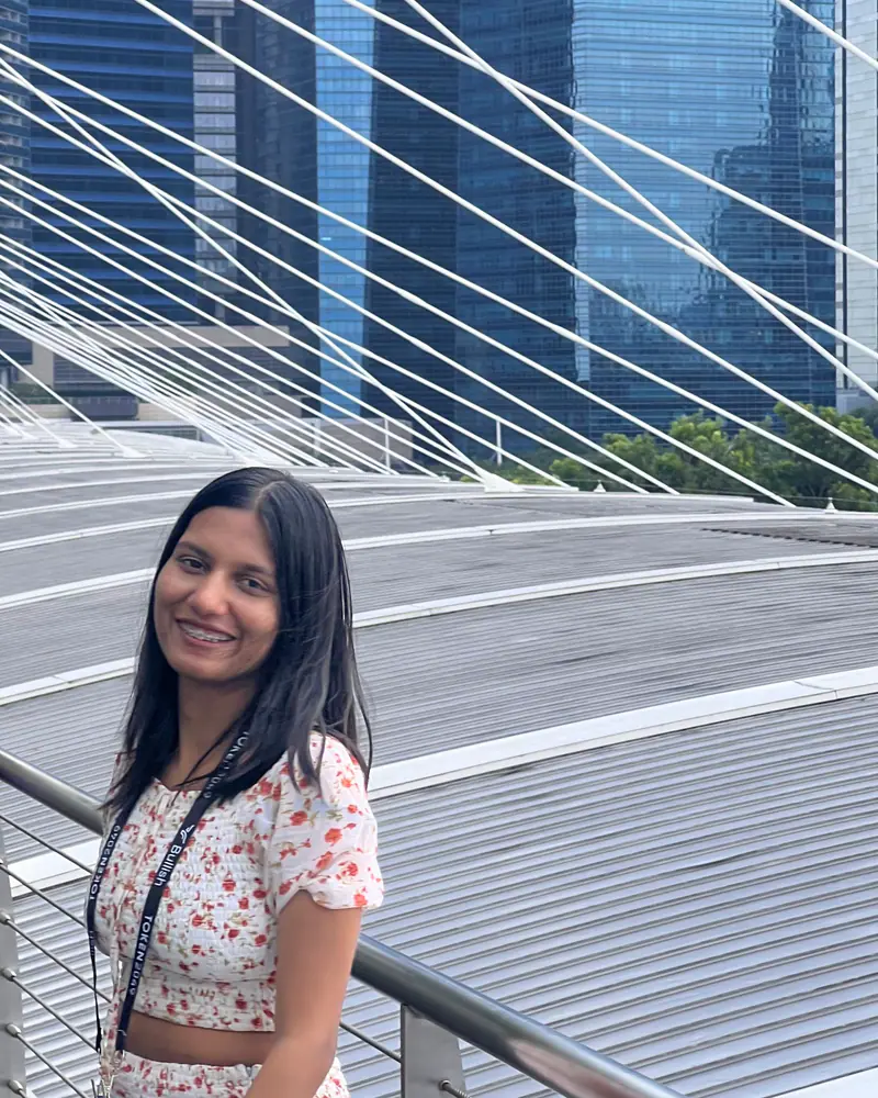 Shilika Jain on a Marina Bay footbridge in Singapore, wearing a conference lanyard