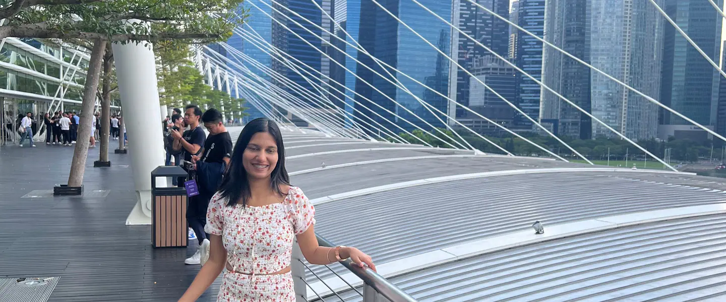 Shilika Jain in a floral dress on a Marina Bay footbridge with the Singapore skyline behind her