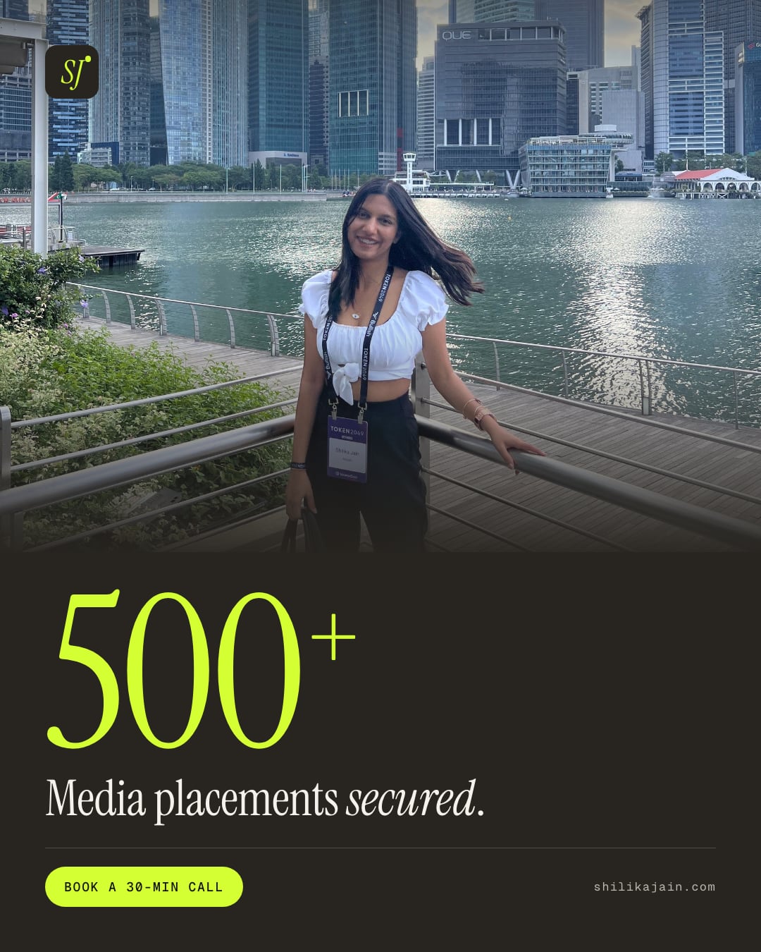 500+ Media placements secured. Photo: Shilika Jain at the Marina Bay railing with the Singapore financial district skyline behind her.